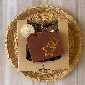 A brownish square soap with handpainted golden stars. The bar has a wavy top decorated with an orange slice.