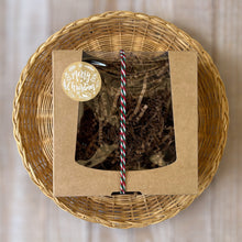 Load image into Gallery viewer, A kraft box with a transparent lid filled with brownish soap, tied with a festive white, red, and green rope and adorned with a Merry Christmas sticker.