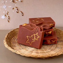 Load image into Gallery viewer, A red-brownish square soap with handpainted golden stars. The bar has a wavy top decorated with an orange slice.