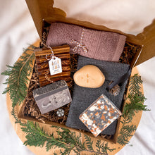 Load image into Gallery viewer, Woods and Mosses men&#39;s self-care gift basket for Christmas arranged in a kraft box. Contains various grooming items like soaps, facial towel, soap dish and exfoliating pouch. Decorated with organic decor for a festive Christmas touch.