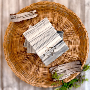 A square soap bar with a birch bark pattern in white, gray, and black, featuring a stamped Woods and Mosses logo in the corner. Ideal for gifting or as a decorative bathroom accent.