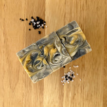 Charger l&#39;image dans la galerie, A soap with distinct white, black, and yellow layers, featuring a textured top. 