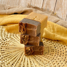 Load image into Gallery viewer, A stack of three handcrafted soap bars with a light beige bottom and a rich brown top. The bars have textured tops adorned with orange peel. 