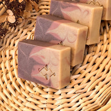 Load image into Gallery viewer, Handmade soap bar with beige, dusty rose, and brown swirls. The Woods and Mosses company logo is prominently displayed in the lower corner.