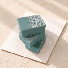 Load image into Gallery viewer, Three greenish-blue artisan soap bars stacked loosely, each featuring delicate white lace decoration.