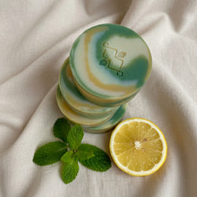 Load image into Gallery viewer, Stacked handmade soaps in lemon and peppermint swirl pattern with round shape.