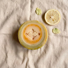 Load image into Gallery viewer, Round artisan soap with pale green and yellow swirl pattern and Woods and Mosses stamped logo