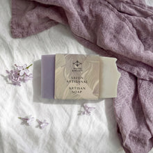 Load image into Gallery viewer, Packaged lilac artisan soap bar with visible mauve and cream ends and branded paper sleeve
