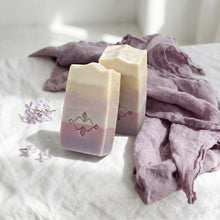 Load image into Gallery viewer, Two tall lilac soap bars with pastel cream and mauve layers, wavy tops and stamped Woods and Mosses logo