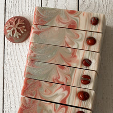 Load image into Gallery viewer, Set of artisan Christmas soap bars with cream, red, and mint-green swirls topped with shimmering mica and glossy red embeds. Each slice features a festive marbled design, resembling peppermint candy, crafted as natural cold process holiday soap.