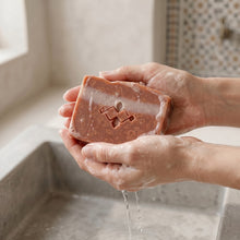 Load image into Gallery viewer, Wet Moroccan clay soap bar with white stripe, stamped logo, speckled texture, and light foam