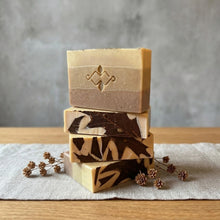 Load image into Gallery viewer, Four handmade Moroccan Rhassoul clay soap bars stacked, with logo-stamped face and oak leaf patterned tops.