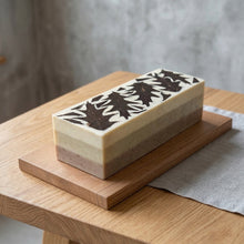 Load image into Gallery viewer, Whole loaf of Moroccan Rhassoul clay soap with layered beige body and oak leaf patterned top.