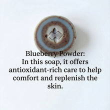 Load image into Gallery viewer, Single round artisan soap bar with blue and brown layered rings and a carved geometric center