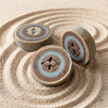 Load image into Gallery viewer, Three River Stone round soap bars with blue and berry-toned rings, shown from front and side.