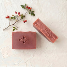 Load image into Gallery viewer, Two rosehip artisan soap bars, one face-up with embossed logo and one turned to show the textured hand-cut side.