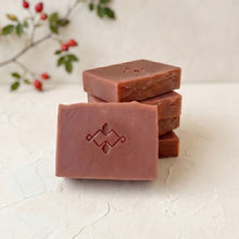 Load image into Gallery viewer, Rosehip artisan soap with one front-facing embossed bar and four stacked bars behind, showing smooth faces and hand-cut edges.