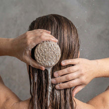 Load image into Gallery viewer, Round floral solid shampoo bar lathering on wet hair during wash, natural handmade hair care product.