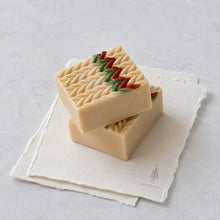 Charger l'image dans la galerie, Handmade cream Christmas sweater soap bar standing on folded white cloth with red and green accents