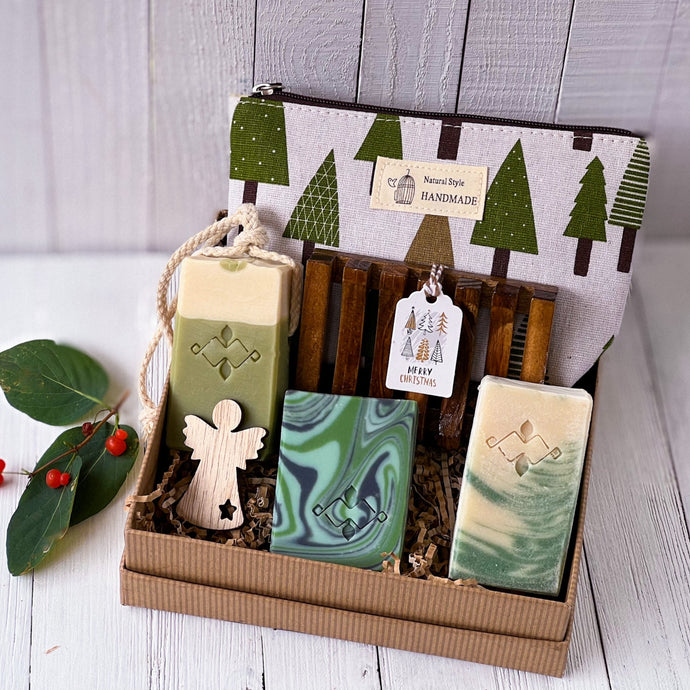 Vegan bath and body gift set with three handcrafted soaps, wooden soap dish, seasonal tree-print pouch and a wooden angel. Packed in crinkle paper and kraft box. Handmade by Woods and Mosses.