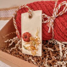 Load image into Gallery viewer, Rectangular white wax tablet embellished with a miniature pumpkin, calendula petals, orange peel, and whole cardamom. Features a white and beige decorative rope threaded through a metal eyelet.