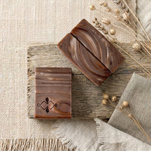 Load image into Gallery viewer, Two handmade artisan soap bars, one stamped and one showing brown wood-grain swirl.