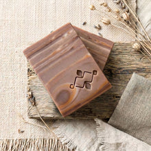 Load image into Gallery viewer, Two handmade artisan soap bars stacked diagonally with brown wood-grain swirl and stamped logo.