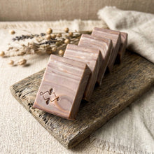 Load image into Gallery viewer, Four handmade artisan soap bars angled in a row, front bar stamped with brown wood-grain swirl.