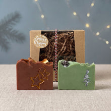 Load image into Gallery viewer, Two hand-painted Christmas soap bars in brown and pale green displayed in front of a kraft gift box with festive twine.