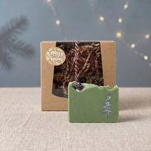 Load image into Gallery viewer, Pale green Holiday Pine soap bar with a hand-painted silver tree and small pinecone displayed in front of its kraft gift box.