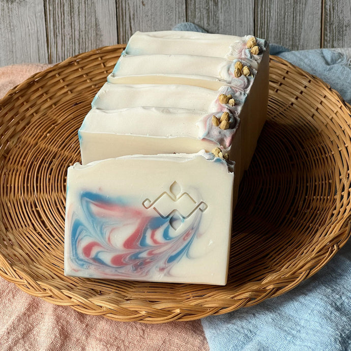 Group of artisan jasmine soaps with dried botanicals, arranged in a shallow basket