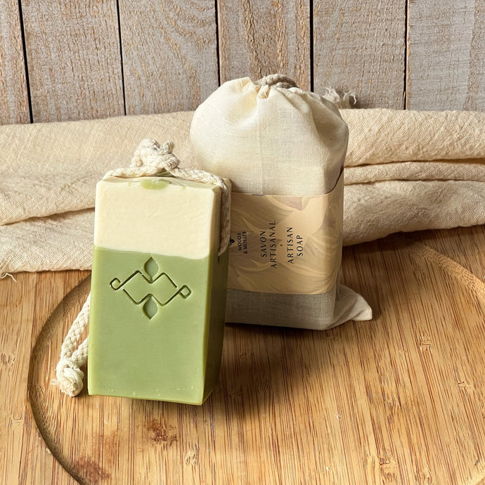 Front view of handmade matcha latte soap on a rope, showing its green and cream layers with embossed design. Vegan, cold process bar with cotton rope.