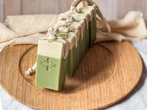 Line of vegan matcha soaps on a rope, arranged diagonally on a wooden surface. Natural skincare bars with embossed design and smooth top swirl.