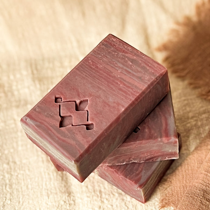 Mocha mousse artisan soap bar with marbled pattern, placed on warm-toned fabric for eco-conscious skincare branding.
